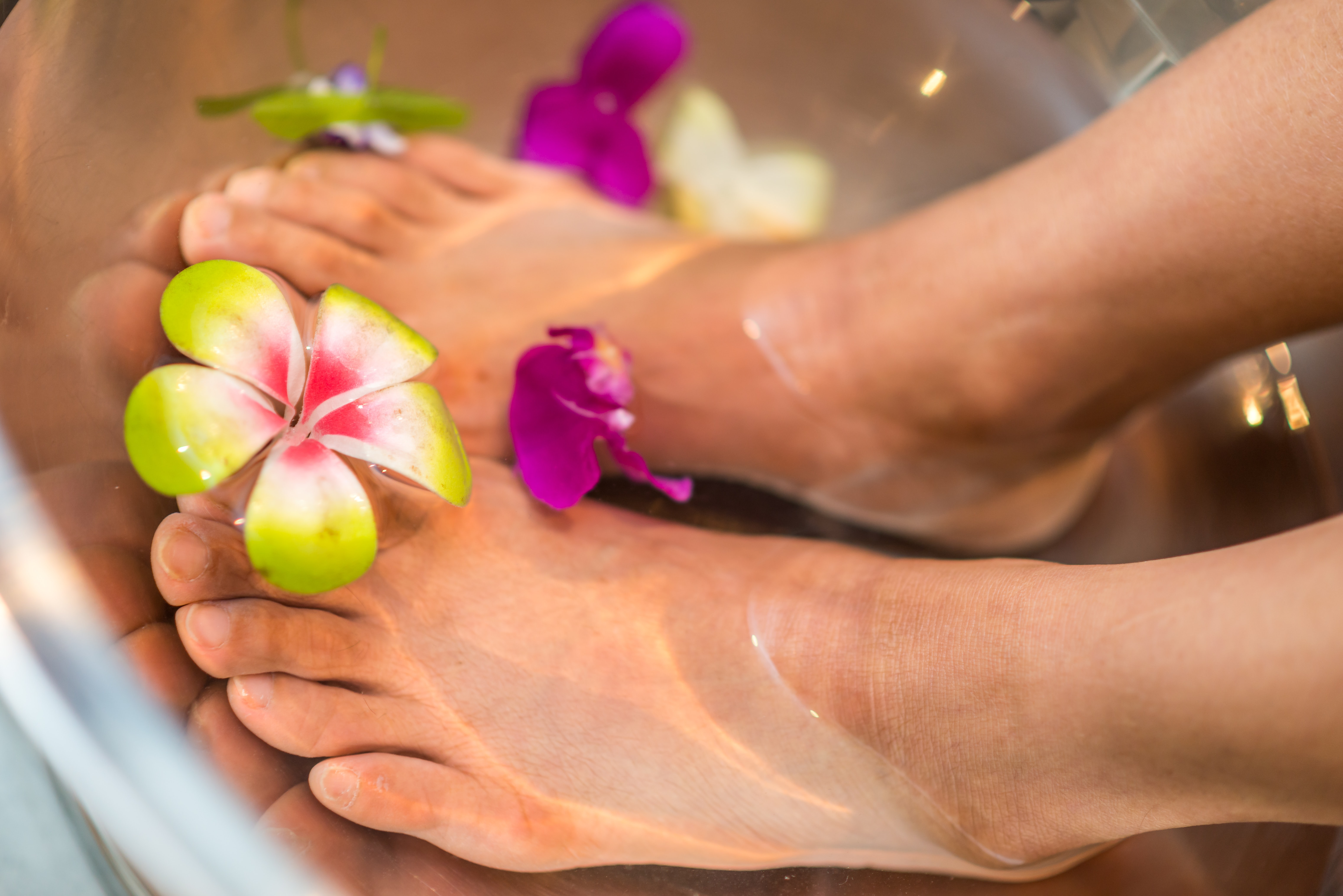 Feet in a basin of water with flowers.